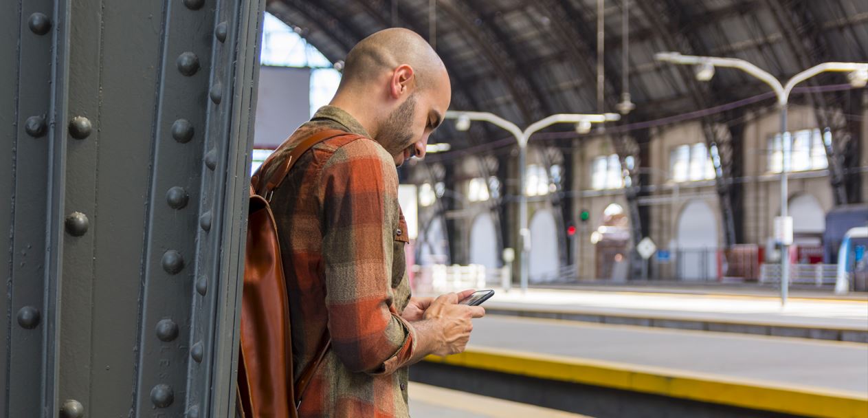 man on train platform on phone buying retail 